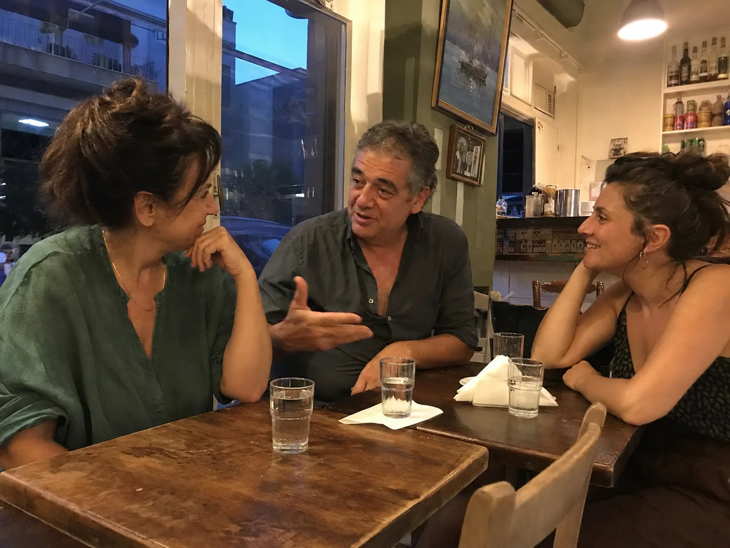 Recreación de la escena de Atenas: un hombre conversa con dos mujeres adultas en un bar